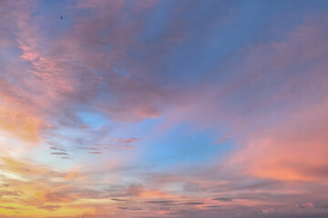 Fototapeta premium Soft pastel sunset clouds spreading across the evening sky with pink and blue tones. Calm outdoor atmosphere featuring layered cloud textures and fading daylight.