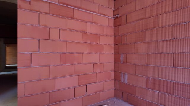 Unfinished room interior of house under construction. Brick red walls. New home.