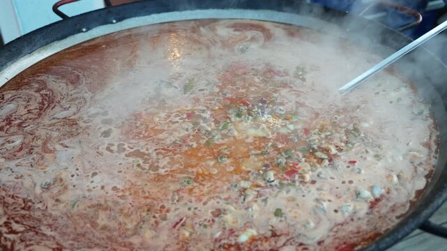 Sizzling seafood paella with shrimp and mussels cooking in a giant traditional pan. Authentic Spanish street food steaming at an outdoor festival, a delicious culinary experience.