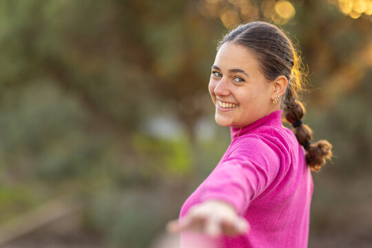 young woman looking back over shoulder and reaching out to follower