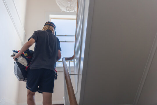 Young person carrying a laundry basket up the stairs, chores and daily life
