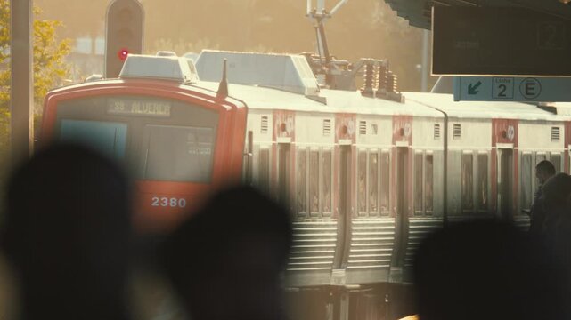 People wait at train station during sunset near city