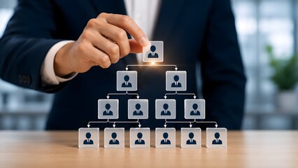 Naklejka premium Hand placing top transparent cube with person icon completing a pyramid structure of corporate leadership and management