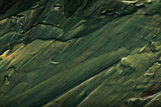 Abstract dark green paint texture background with gold metallic brush strokes and shimmer