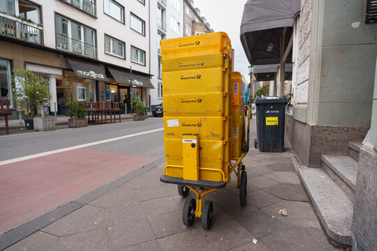 Dusseldorf, Germany - October 31 2025: Deutsche Post delivery cart waits beside quiet storefronts on a calm city street in Altstadt central district
