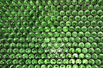 Full frame wall with empty green beer bottles bottoms. Alcohol theme. Endless rows of wine bottles. Green glass bottle wall with sunlight from behind © frenta