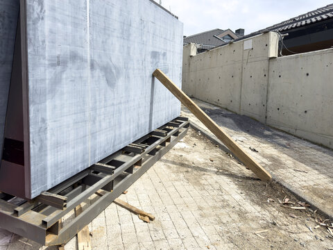 View of large grey stone slabs resting on a metal frame supported by a wooden beam at a construction site with a concrete wall Sariyer, Istanbul, Turkiye.