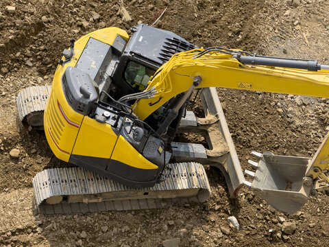 View of a yellow excavator with metal tracks and a hydraulic arm on a dirt construction site in Sariyer, Istanbul, Turkiye.