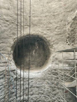 View of a large circular tunnel opening in a concrete wall at a construction site with scaffolding and cables in Sariyer, Istanbul, Turkiye.