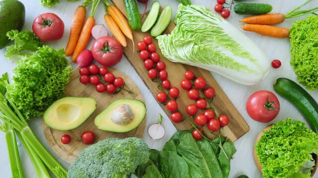 Fresh assorted vegetables arranged on wooden cutting boards and table