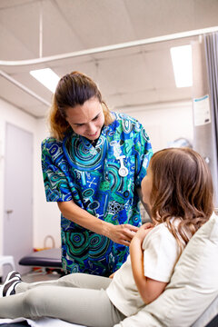 Medical practitioner cheerfully speaking with the little girl as she injects the vaccine