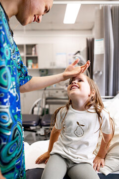 Nurse gently examining child's temperature on forehead in clinic setting
