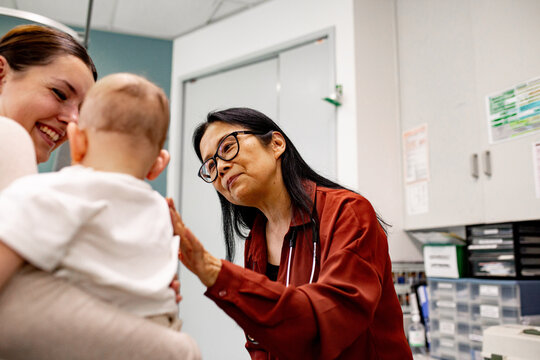 Doctor gently patting the infant's shoulder before examining
