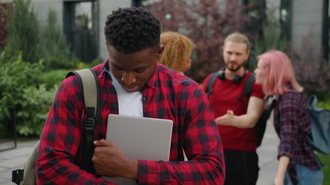 Upset African American guy male student bullied man feeling despair bullying by multiracial students bad gossiping showing thumb down judge disrespect teasing mocking bully at city college university