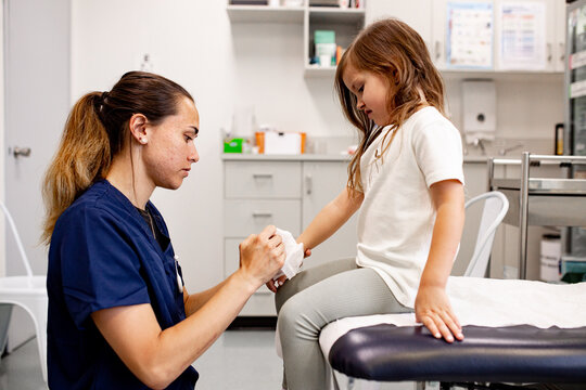 Medical professional bandaging child&rsquo;s hand in clinic