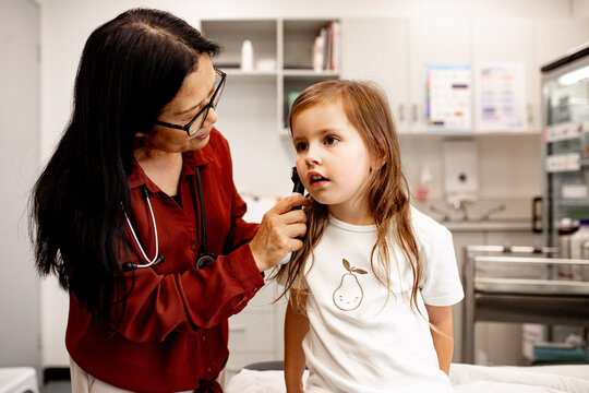 ENT doctor performing an ear examination with an otoscope in a clinic