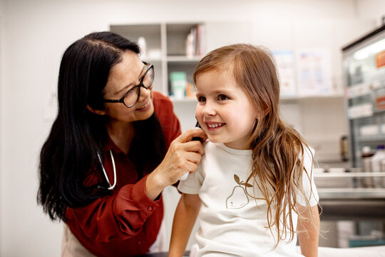 Young girl smiling as her doctor examine her ear with otoscope