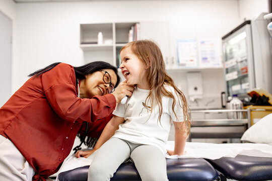 ENT doctor using an otoscope while engaging positively with a child in a clinic