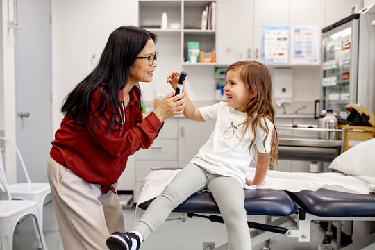 Healthcare professional using otoscope with child in clinic