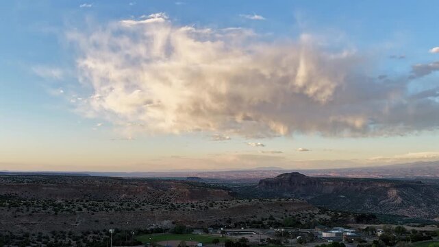 4K drone timelapse flies towards a shifting raincloud glowing with sunset colors over a lush green city park. Cinematic aerial footage reveals moody weather contrasting with urban recreational space.
