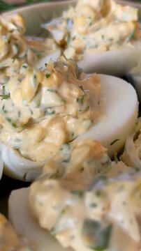 Creamy deviled eggs arranged on a serving platter, styled as a homemade party appetizer with herb-speckled filling in a close-up food presentation.