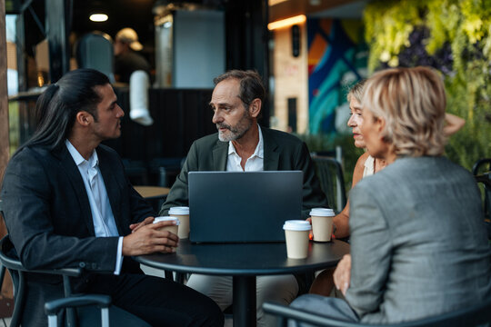Businesspeople meeting outdoors, discussing projects over coffee