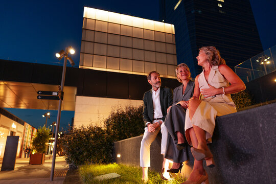 Mature friends conversing in city at night