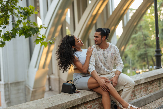 Happy diverse couple bonding on urban bridge