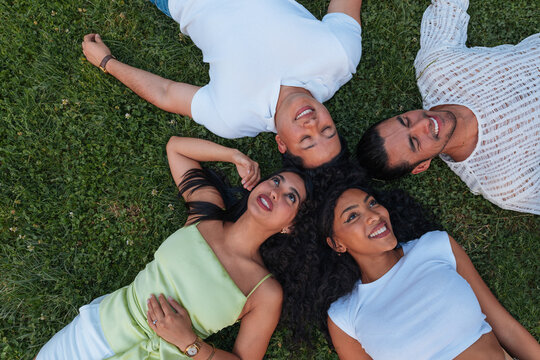 Diverse friends lying on grass in circle, smiling