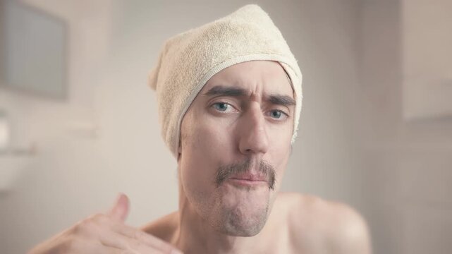 Comical mustached man in bathroom with towel on head gestures stop sign, saying enough, quit it, cut it out, with playful thoughtful expressions