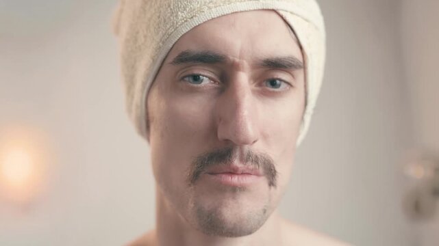 Funny mustached man in bathroom with towel turban winks and smirks