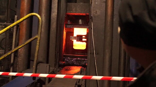 A red-hot ingot pulled from the furnace, ready in the punch press for further processing. The punch press for producing pressure cylinders (often steel or aluminum).