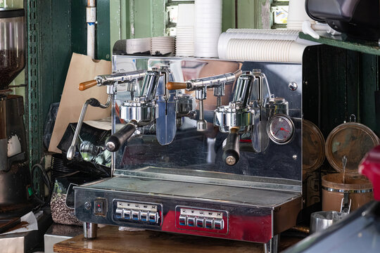 View of a professional chrome espresso machine with portafilters and stacked paper cups in a local cafe in San Jose, San Jose Province, Costa Rica.