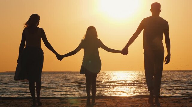 Silhouette family walk toward sunset on beach holding hands while waves gently wash ashore creating a serene golden hour scene.
