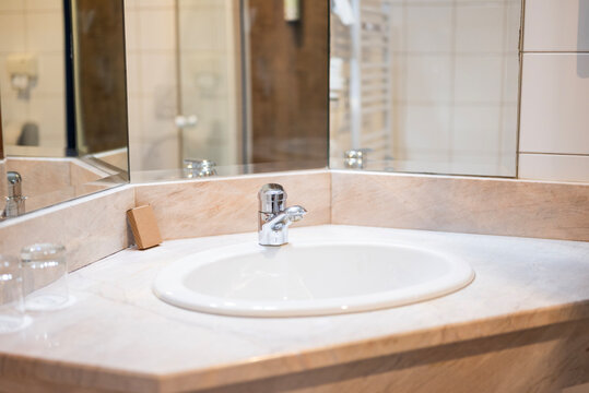 Elegant hotel bathroom interior with a clean white sink, chrome faucet, and marble countertop reflection in the mirror.