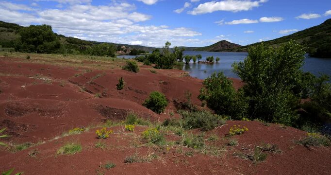 Red landscape surrounding te artificial lake of Salagou, Occitania, Southern France.