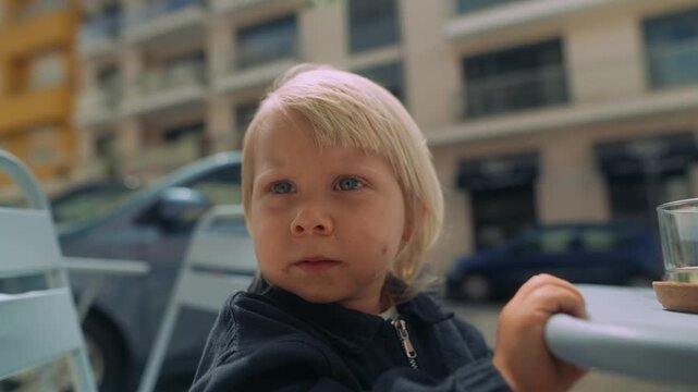 Young child turns head happily in gentle outdoor urban setting
