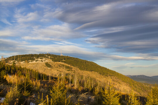 View of Schockl mountain with its transmission tower and forested slopes under a sky with unique cloud formations Graz, Styria, Austria.