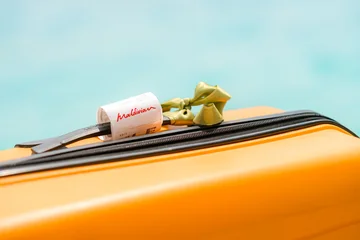 02.05.25, Male, Maldives - bright orange suitcase displays Maldivian , open to a calming pool scene, turquoise and red, beach escape, tropical getaway, idyllic vacation, island dreaming. © FOTO_STOCKER