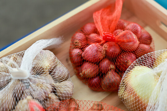 Fresh red shallot onion garlic packed in mesh net bag inside wooden crate box ready for healthy vegetarian meal preparation bringing natural culinary delight