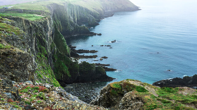 Wide panoramic view of the Old Head of Kinsale cliffs and green headlands at rainy day, Cork, Ireland.