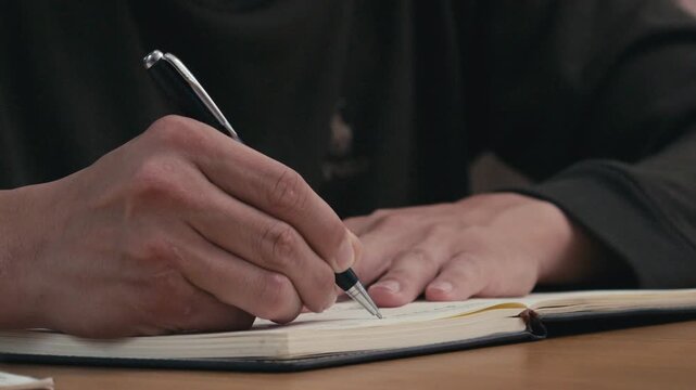 Close-up of a person writing with a pen on paper, showing note taking, planning, studying, journaling, and daily productivity on a desk.