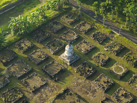 Aerial view of Plaosan Kidul Temple featuring a central white stupa surrounded by ancient stone foundations and lush tropical greenery in Kecamatan Prambanan, Jawa Tengah, Indonesia.