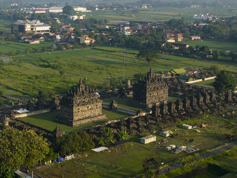 Aerial view of Plaosan Lor Temple with its two main ancient stone structures and surrounding green rice fields at Kecamatan Prambanan, Jawa Tengah, Indonesia.