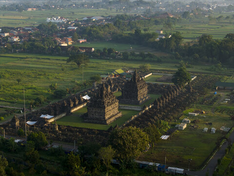 Aerial view of Plaosan Lor Temple complex featuring twin main temples and surrounding stupas amidst lush green fields and trees Kecamatan Prambanan, Jawa Tengah, Indonesia.