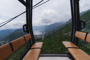 Obraz premium Inside view of a cable car cabin with a breathtaking panoramic outlook of mountains, sea bay, and clouds.