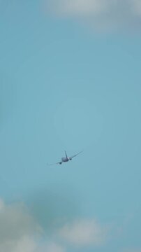 Commercial jet approaching with wings spread against blue sky and clouds, flight direction and transport network theme, vertical orientation. Aviation sector facing increasing fuel expenses and