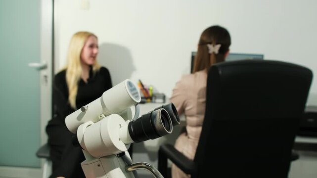 Modern colposcope and gynecologist talking to patient in medical office slow motion. Tool for detailed examination of cervix vagina and vulva