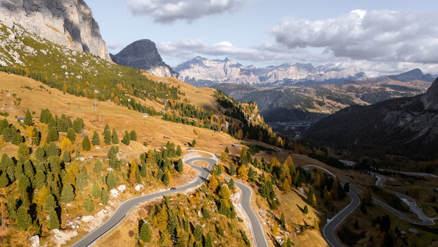 Aerial view of the winding Gardena Pass road featuring hairpin turns and autumn larch trees in the Dolomites Corvara, Trentino-Alto Adige, Italy.