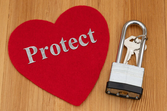 Protect text on a red heart with silver padlock lock on a wood desk